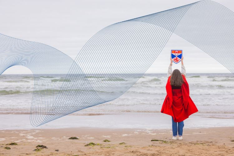 student in red gown on beach
